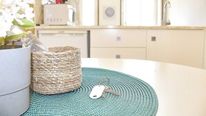 Una cocina con una cesta trenzada, una planta en maceta y un juego de llaves sobre un tapete redondo.