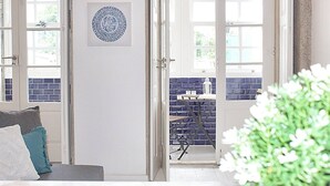 Una habitación con una puerta, una vista a través de ella, una ventana y una planta.