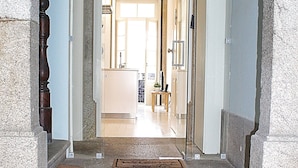 Una escalera de piedra que lleva a un vano con un panel de vidrio, una puerta de madera y un felpudo en los escalones.