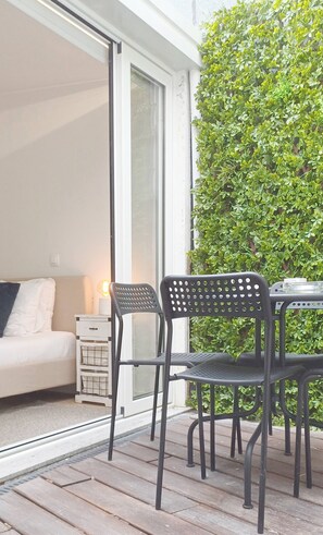 Eine Terrasse mit Tisch und Stühlen, einem weißen Sofa und einer Glastür.