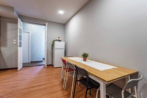 A dining area with a wooden table, four chairs, a potted plant, and a white refrigerator. - Experience the Charm  Porto Apartment with Terrace (Oporto)