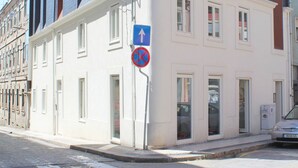 Kulmassa sijaitseva rakennus, jossa on valkoinen julkisivu, useita ikkunoita ja sininen kyltti, joka osoittaa pysäköintikiellon.