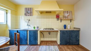 Eine Küche mit gelber Wand, weißen Fliesen, einer Holz Arbeitsplatte, einem Gasherd und blauen Schränken.