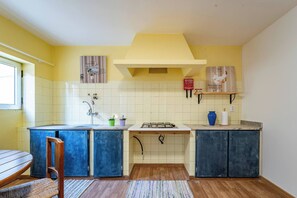 Eine Küche mit gelber Wand, weißen Fliesen, einer Holz Arbeitsplatte, einem Gasherd und blauen Schränken.