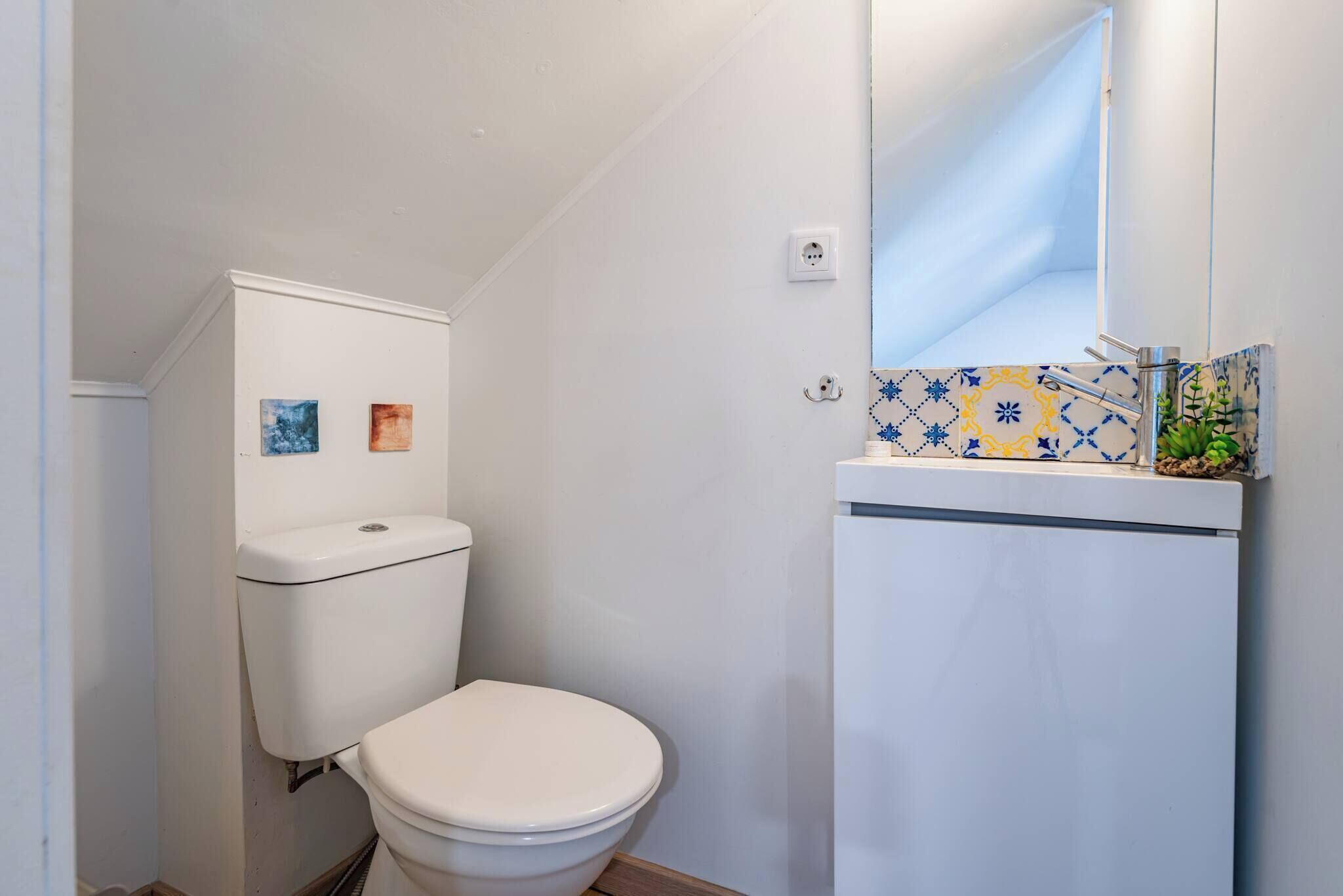 A small bathroom with a toilet, a sink, and a mirror.