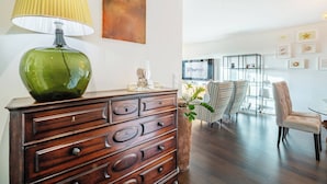 Een moderne woonkamer met een houten dressoir, een groene lamp en een glazen salontafel.