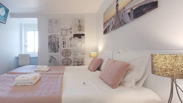 Ein Hotelzimmer mit zwei Betten, einem an der Wand befestigten Fernseher, einem großen Fenster und einer dekorativen Wandverkleidung.