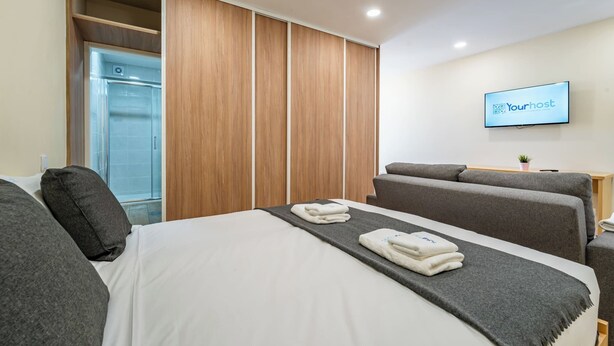 Ein Hotelzimmer mit Bett, Fernseher, Kleiderschrank und Dusche.