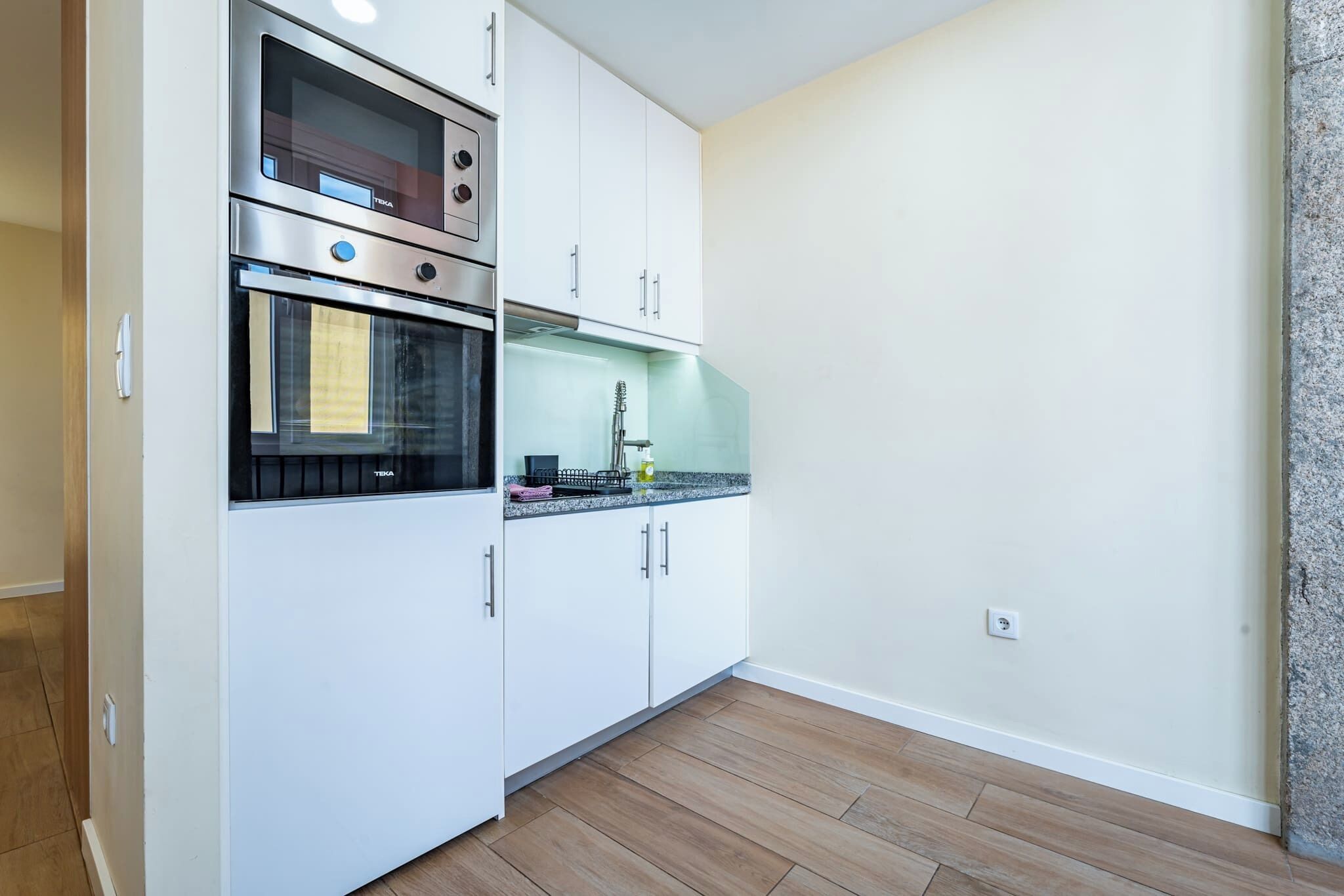 A kitchen with white cabinets, a stainless steel oven, and a granite countertop.