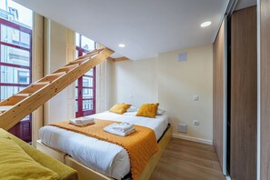Ein Schlafzimmer mit Bett, einer Holztreppe, einem Fenster und einem Kleiderschrank.