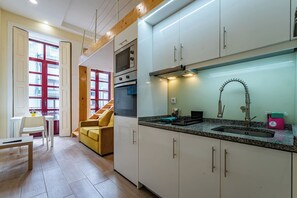 Eine moderne Küche mit weißen Schränken, einer Edelstahl-Spüle und einem eingebauten Backofen.