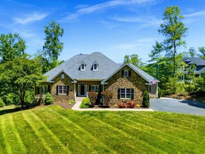 A two-story house with a stone facade, a front porch, and a well-maintained lawn.