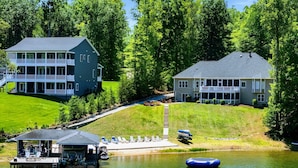 Une propriété au bord du lac, dotée d’un quai, d’une plateforme flottante et d’une grande maison avec véranda.