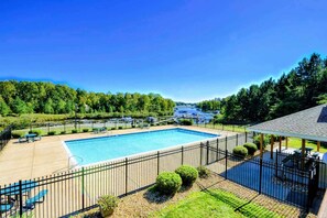 A rectangular swimming pool with a surrounding fence, a covered seating area, and a view of a forested area in the background. - Lakefront Luxury 7BR, 7BA, Beach, Dock, Views (Mineral)