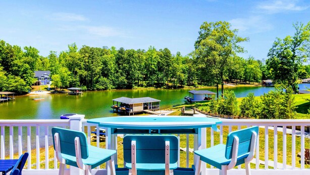 Une terrasse au bord du lac avec des sièges d’extérieur, un quai et une maison en arrière-plan.