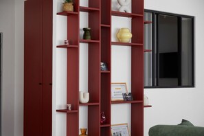 Une étagère rouge sur laquelle sont disposés divers objets décoratifs et un certificat encadré.