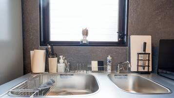 A kitchen with two stainless steel sinks, a window above the sink, and a knife block to the right.