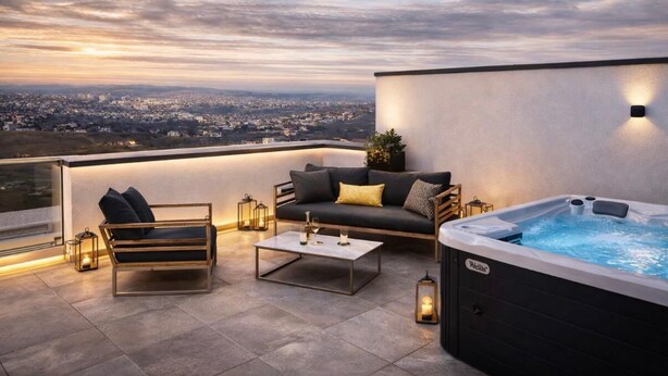 A rooftop terrace with a sofa, coffee table, and hot tub.
