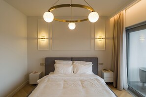Moderni hotellihuone, jossa on suuri sänky, yöpöydät, kattovalaisin ja näkymä ikkunasta.