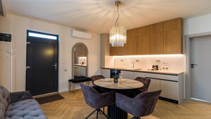 A modern kitchen with wooden cabinets, a round dining table with chairs, and a pendant light.