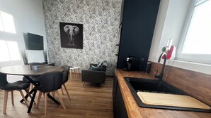 Une cuisine moderne avec un plan de travail en bois, un coin repas doté d’une table ronde et un mur recouvert d’un papier peint à motifs.