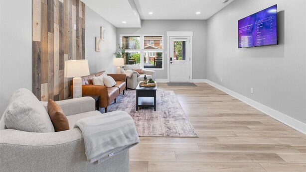 A modern living room with a sofa, coffee table, and a flat-screen TV mounted on the wall. - Freshly renovated 2 story house near downtown Indy (Indianapolis)