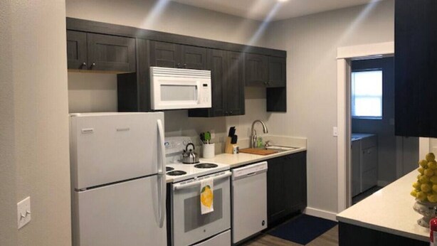 A compact kitchen with a refrigerator, stove, microwave, and sink.