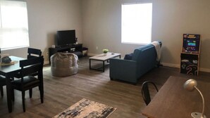 A living room with a sofa, TV, coffee table, and a small table with a lamp.