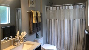 A bathroom with a sink, mirror, towel rack, toilet, and a shower curtain.