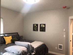 Ein Schlafzimmer mit einem Bett, Kissen, einer Wandheizung und zwei gerahmten Blumenbildern.