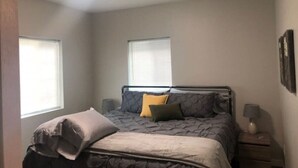 A bedroom with a bed, two bedside tables, a lamp, and a window.
