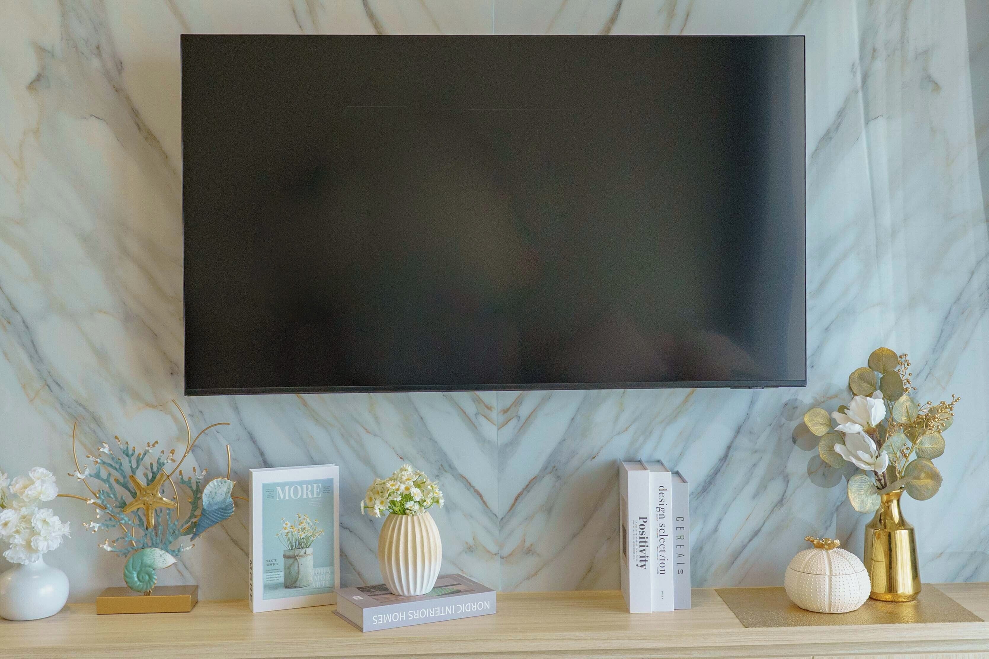 A flat-screen TV mounted on a wall with a marble pattern.