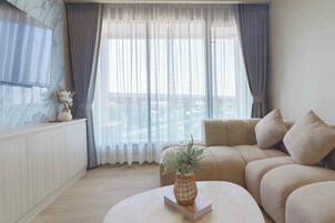 A modern living room with a sofa, a coffee table with a vase, and a TV mounted on the wall.