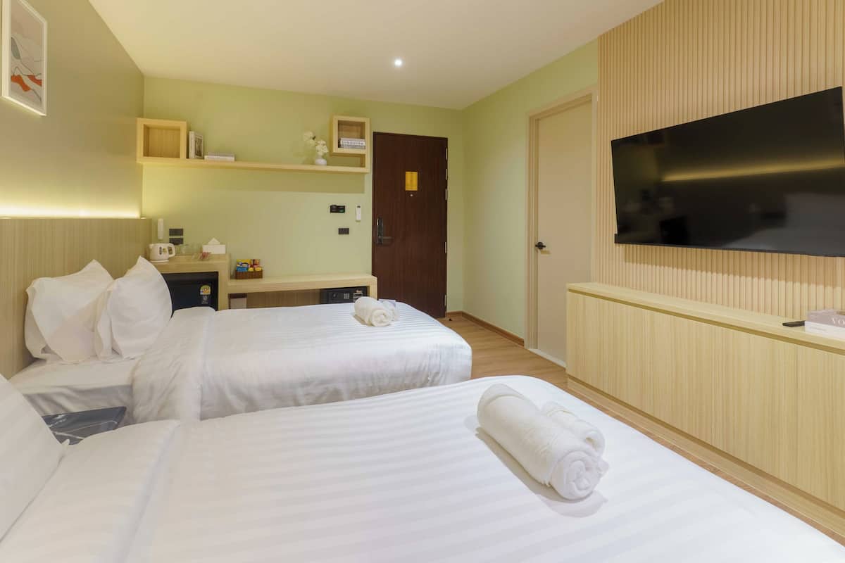 Habitación de hotel con dos camas, televisor, un escritorio pequeño con microondas y pared de panel de madera.