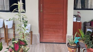 A brown door with a metal handle, potted plants in front, and a window with curtains. - Relax Garden House (Moyobamba)