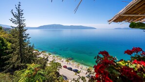 A coastal view with a clear sky, a road leading to a beach, and a mountain range in the distance. - Ellin Apartment (Vlorë)