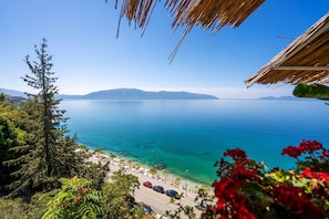 A coastal view with a clear sky, a road leading to a beach, and a mountain range in the distance. - Ellin Apartment (Vlorë)