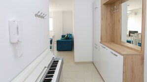 A narrow hallway with a piano, a white wall-mounted phone, and a wooden cabinet with a mirror. - Richard Sea View Apartment (Qendër Vlorë)