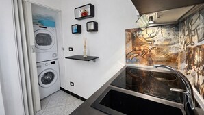 Una cocina compacta con estufa integrada, un lavamanos y un tendedero de pared.
