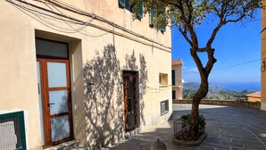 Un edificio con fachada de piedra, puerta de madera y ventana con reja de metal.