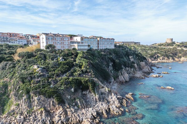 A coastal hotel with multiple buildings, rocky cliffs, and clear blue waters. - Lu Maggiu (Santa Teresa di Gallura)