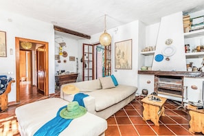 Ein Wohnzimmer mit Sofa, einem Holztisch, einer Pendelleuchte und einem Kamin.