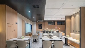 Ένα σύγχρονο εστιατόριο με μπαρ, χώρο για καθιστικό και μια μεγάλη οθόνη.