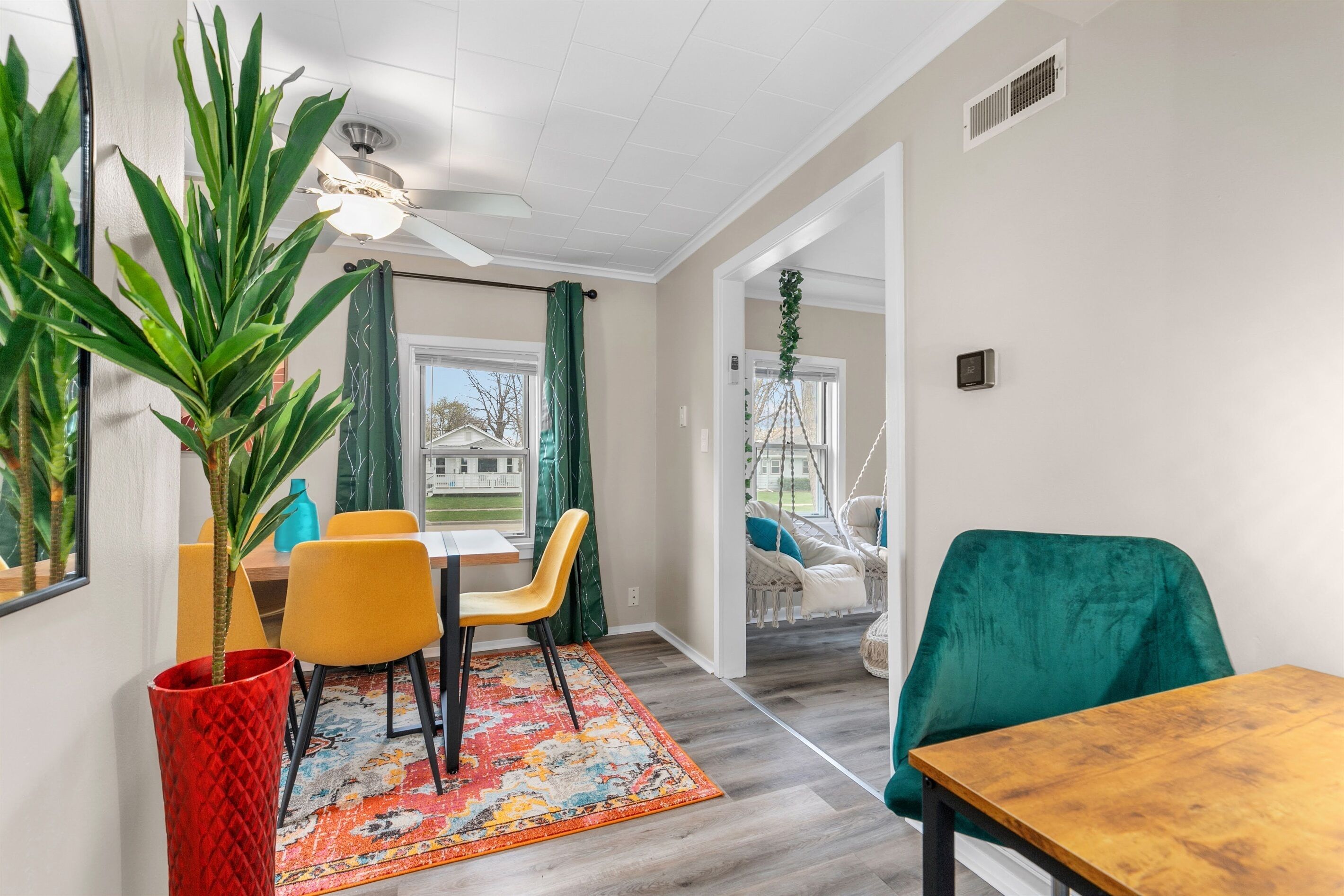 A dining area with a table, chairs, and a large plant.