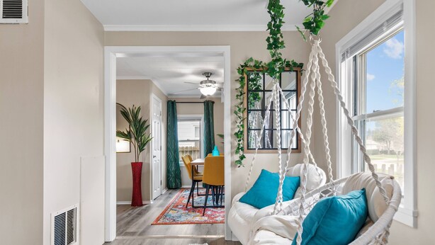 Quarto com uma cadeira suspensa, área de jantar e vista para o exterior.