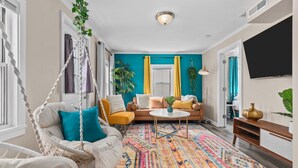 Sala de estar com sofá, cadeira suspensa, mesa de centro e tapete colorido.