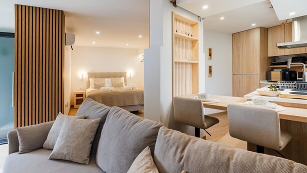 Ett modernt hotellrum med en soffa, en säng, en matplats och ett kök.