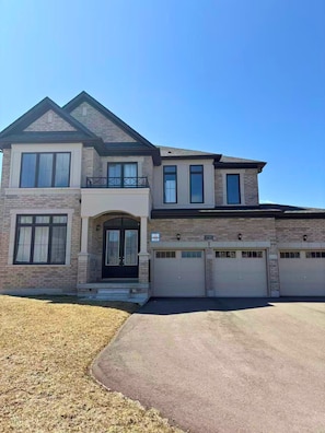 A two-story house with a garage, a front entrance with a porch, and a clear sky.