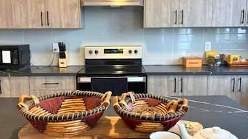 A modern kitchen with wooden cabinets, a black stove, and two woven baskets on a wooden board.