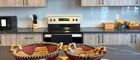 Una cocina moderna con armarios de madera, una estufa negra y dos cestas tejidas sobre una tabla de madera.